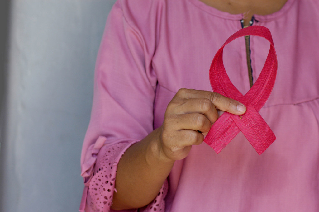 A woman holds a pink ribbon in awareness of Breast Cancer Day. A woman holds a pink ribbon in awareness of Breast Cancer Day.