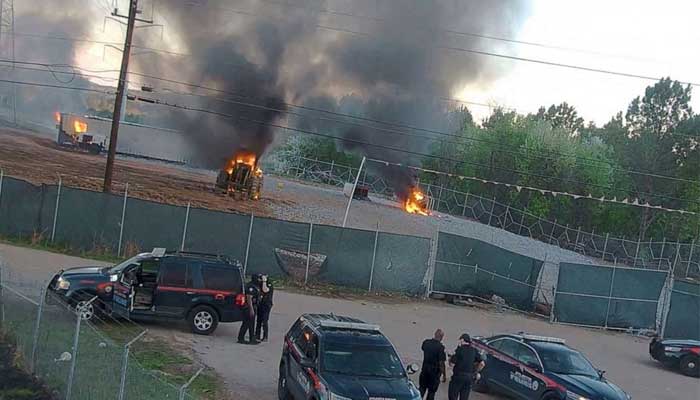 A tractor working at the training center was set on fire by the protestors, police personnel are also present.