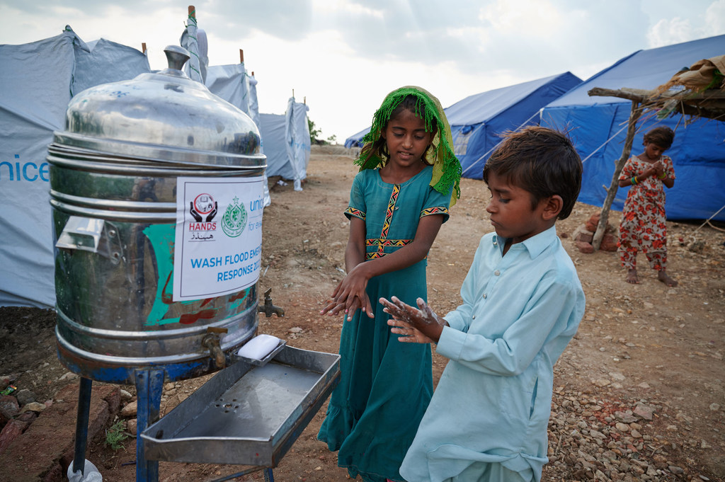 Displaced children wash their hands outside a public toilet at a camp in Sindh Province, Pakistan. Displaced children wash their hands outside a public toilet at a camp in Sindh Province, Pakistan.