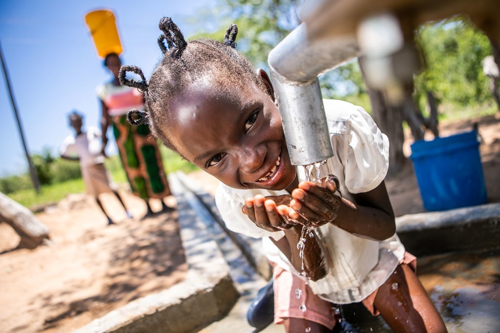 A young girl in Zimbabwe drinks clean and safe water from a well point rehabilitated with the support of the UN.