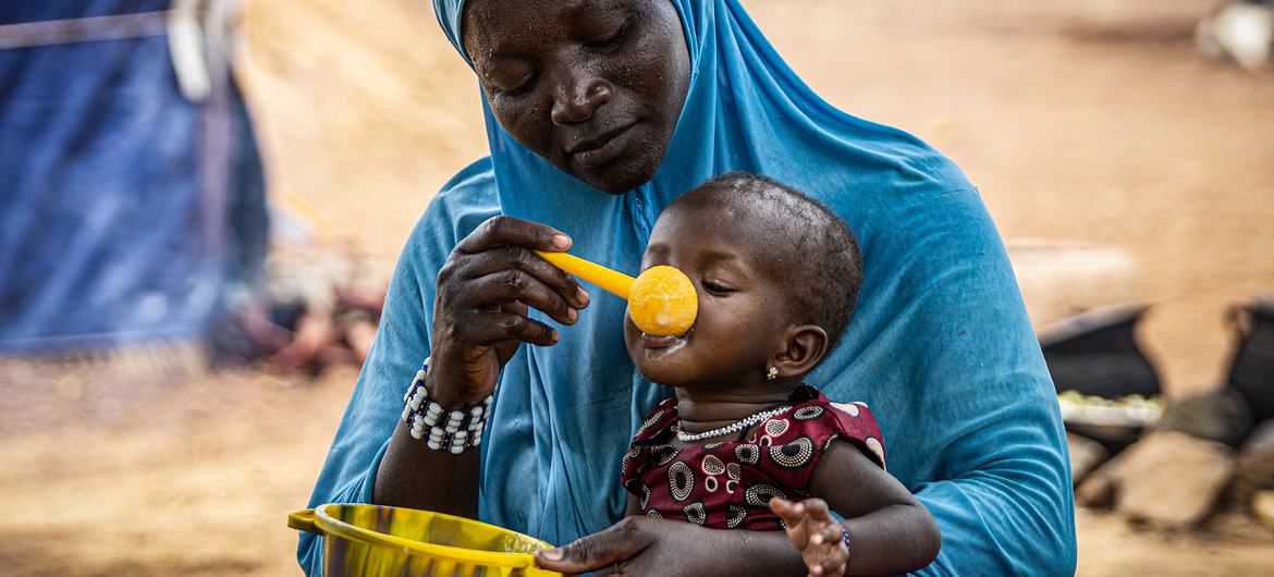A mother gives her 10-month-old daughter porridge in Burkina Faso in the Sahel region, where WFP is providing assistance to prevent malnutrition. A mother gives her 10-month-old daughter porridge in Burkina Faso in the Sahel region, where WFP is providing assistance to prevent malnutrition.