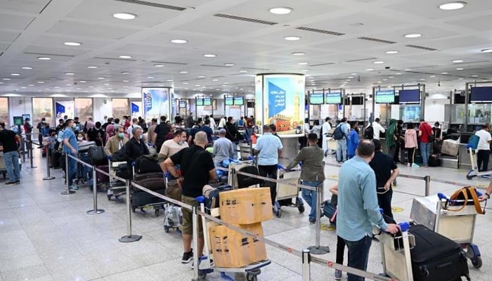 Passengers queue at Kuwait International Airport.