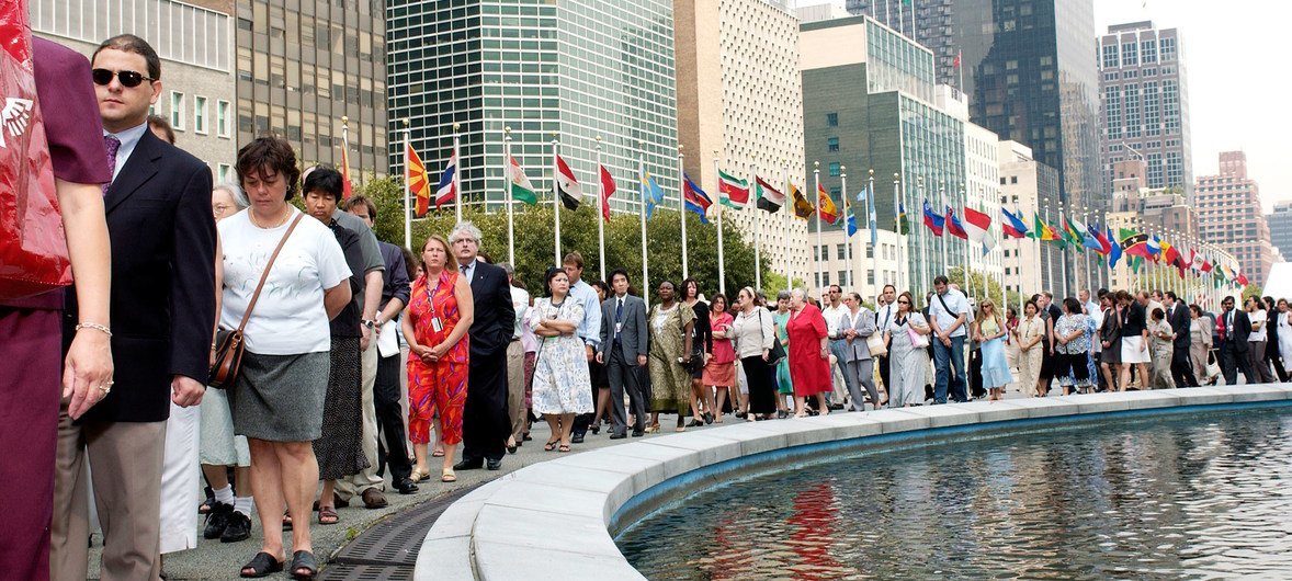 United Nations staff members march around the Secretariat in New York to express their distress over the bombing of the UN Headquarters in Baghdad on 19 August. In the background are the flags of the United Nations members. (26 August 2003)