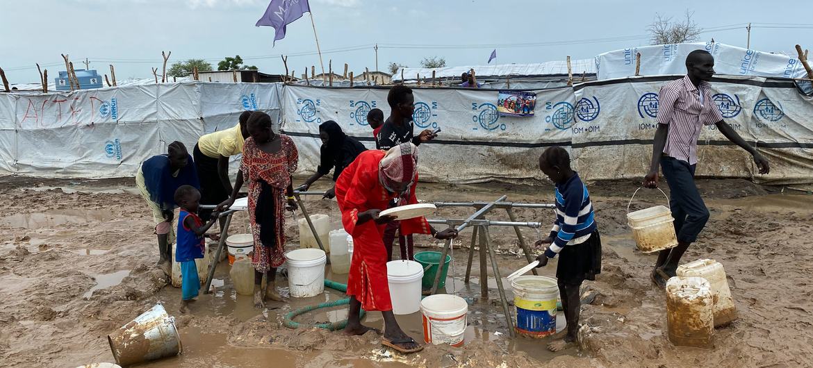 People living in a temporary camp in Renk collect water.