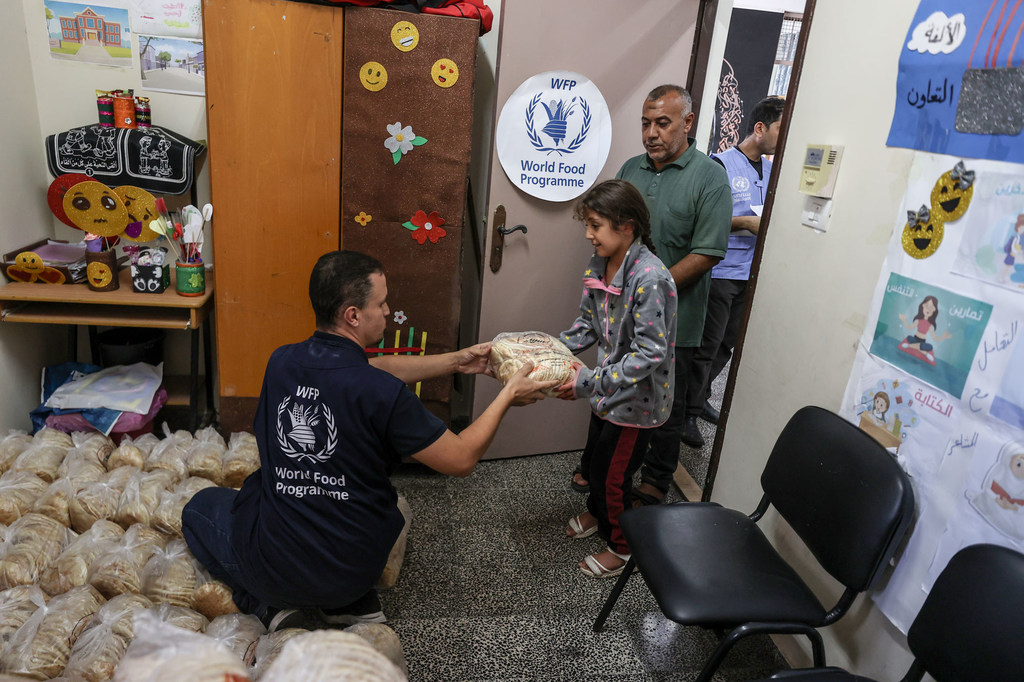 A World Food Programme (WFP) staff member distributes bread to a family sheltered at a UN school in Gaza. A World Food Programme (WFP) staff member distributes bread to a family sheltered at a UN school in Gaza.