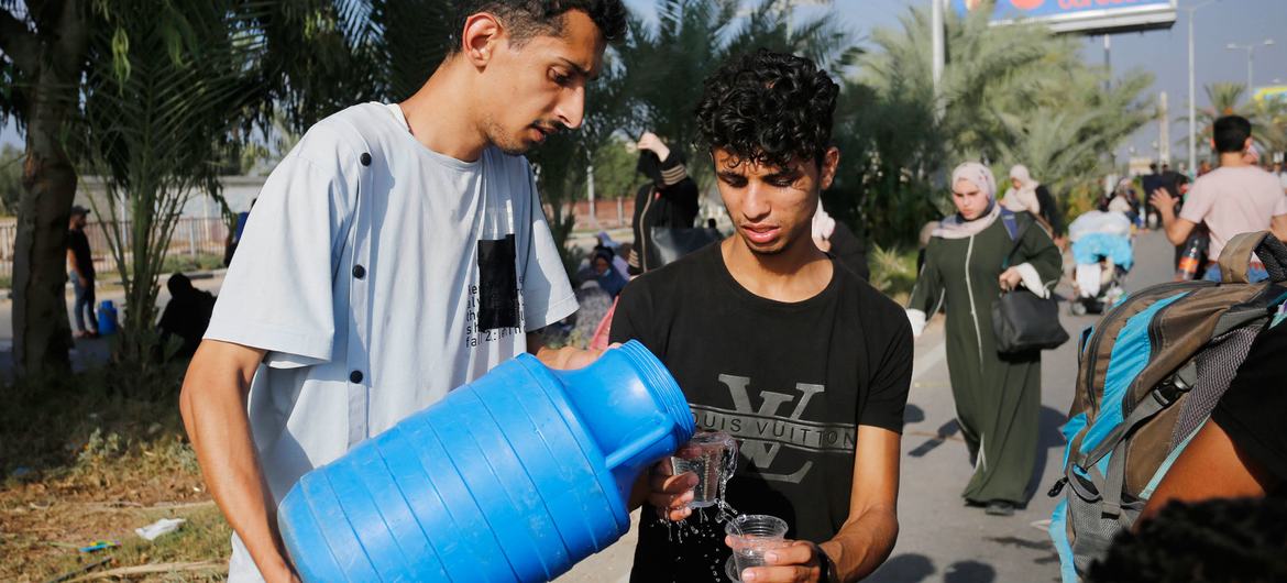 A man and a boy share drinking water in the Gaza Strip. A man and a boy share drinking water in the Gaza Strip.