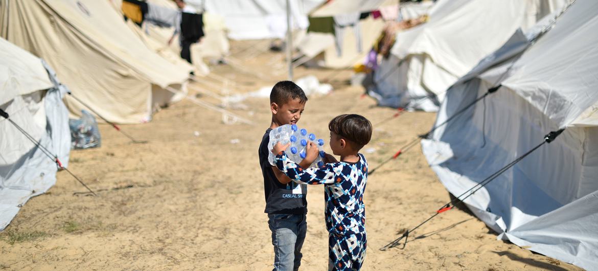 Two young boys carry bottles of water at an UNWRA refugee camp in Khan Younis in southern Gaza.