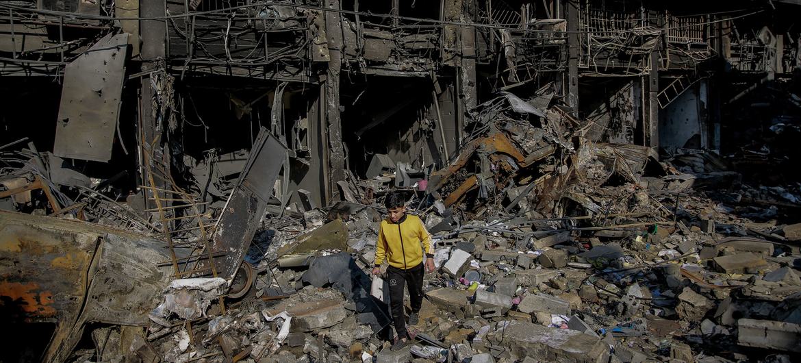 A young boy walks over the rubble of his destroyed home in Gaza City.